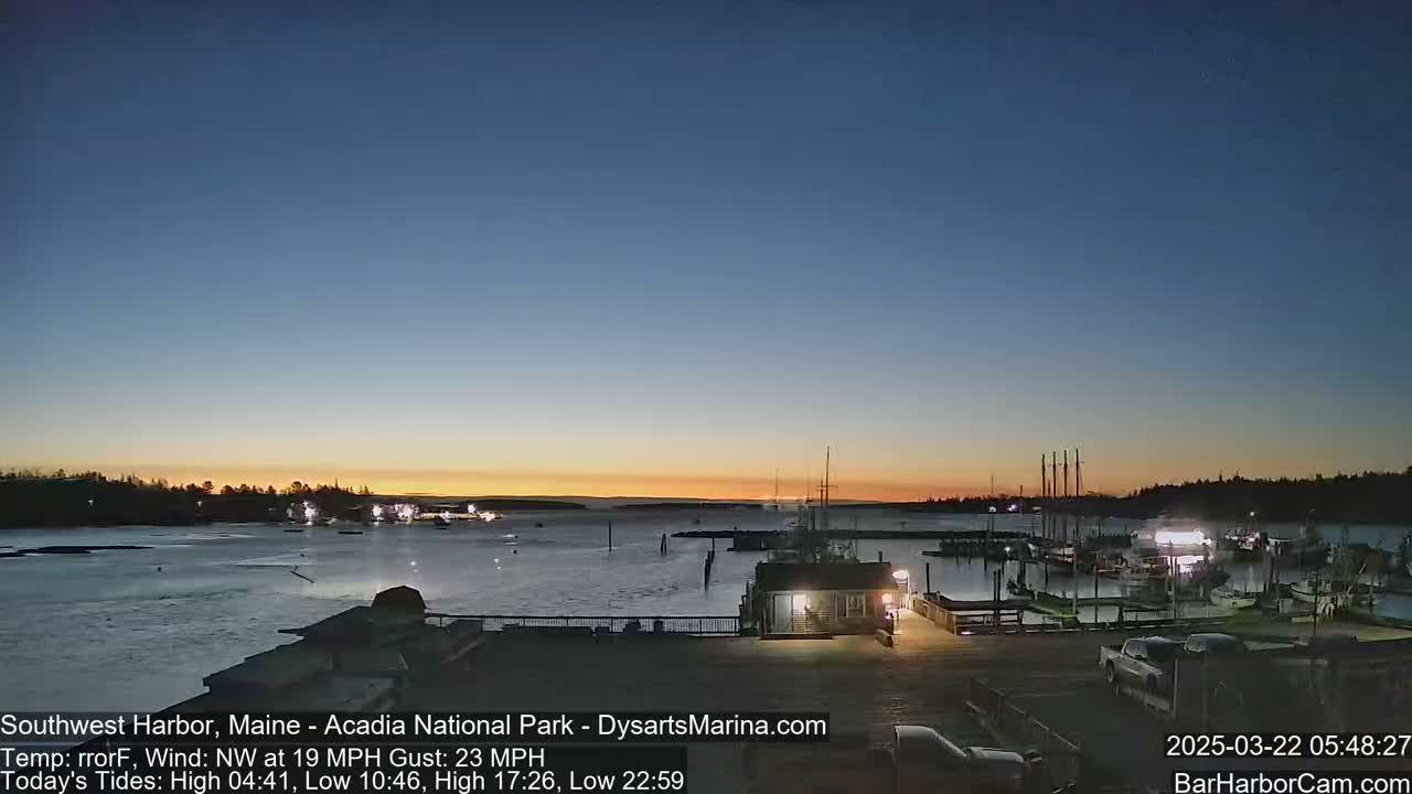 A harbor filled with boats at twilight under a clear sky, with a slight wind.