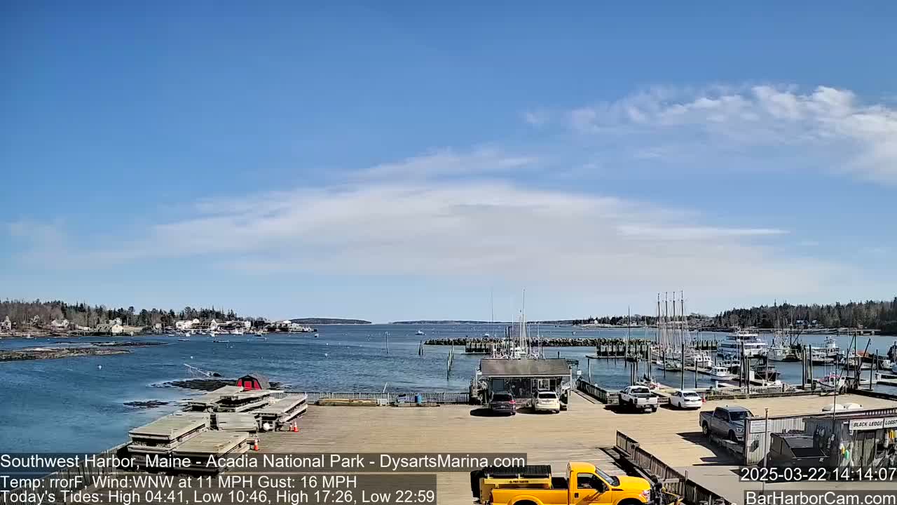A harbor filled with boats under a mostly clear blue sky with a few scattered clouds.