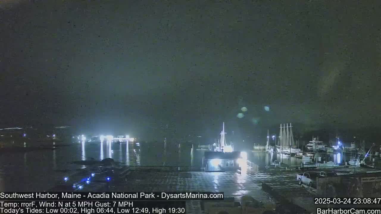 A nighttime view of a harbor with boats docked, under a dark, overcast sky with a north wind.