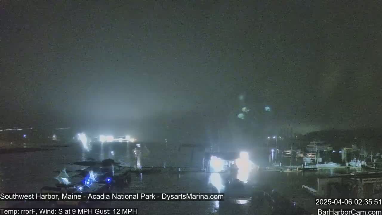 A nighttime harbor scene with boats and buildings is visible under hazy, dark conditions, with a south wind at 9 mph and gusts up to 12 mph.