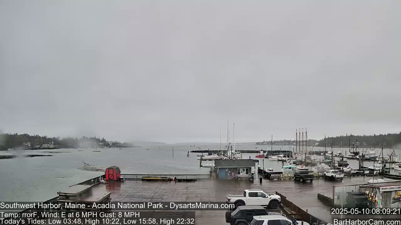 A harbor with boats and vehicles is shown on an overcast day with a light east wind.