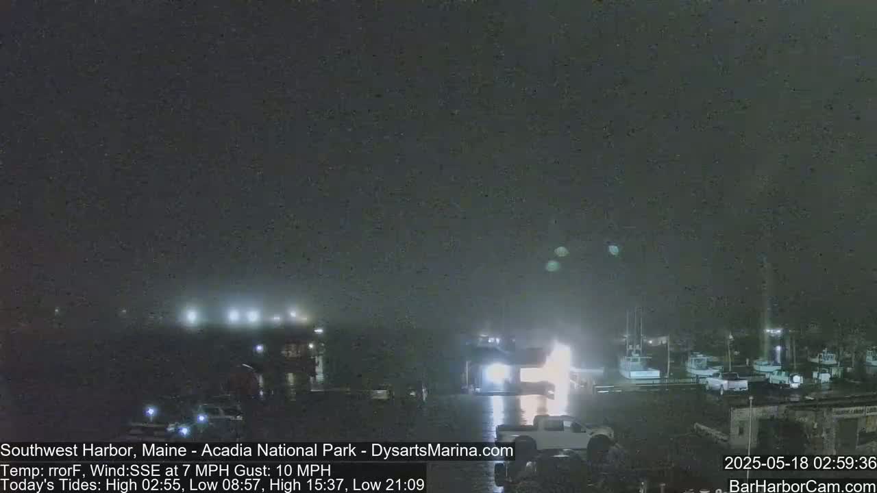 A nighttime view of a harbor with boats moored, under a dark, hazy sky.