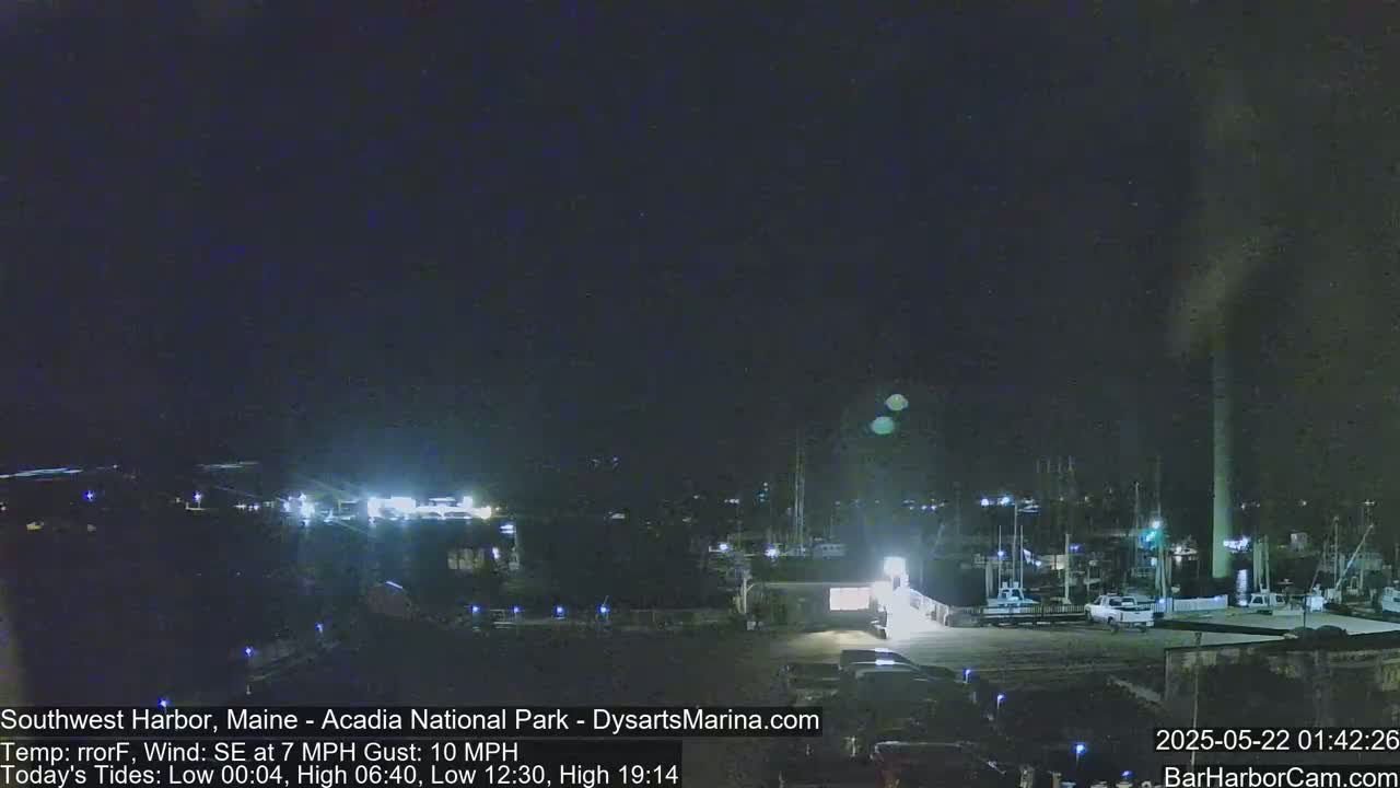 A nighttime view of a harbor with boats docked, under a dark sky with a southeast wind.