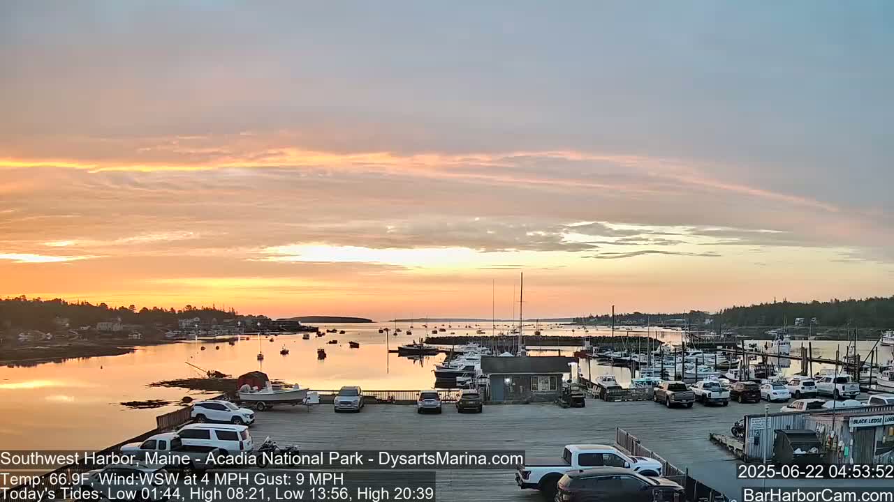 A calm harbor filled with boats at sunset under a pastel sky.