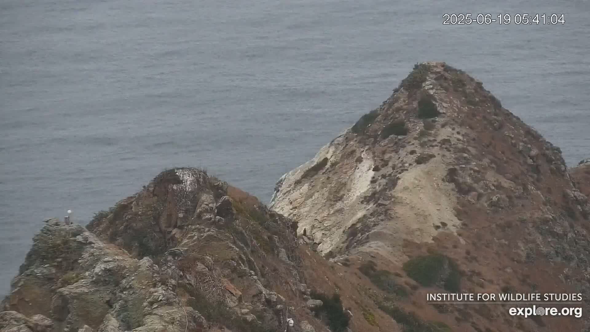 A rocky, mountainous coastline overlooking a calm ocean.