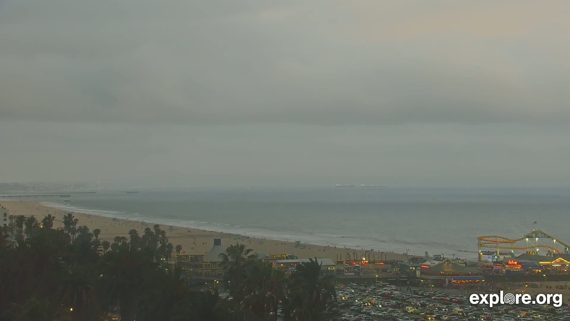 A beach with a pier and amusement park is visible under an overcast sky.