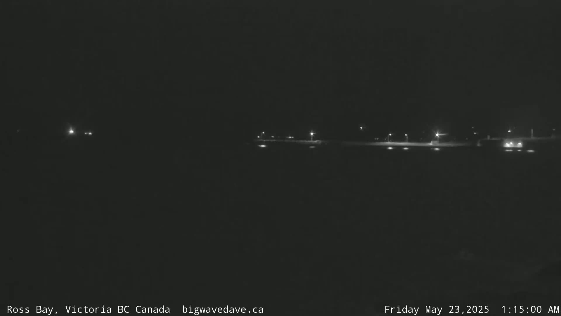 A dark nighttime scene shows a flat, dimly lit area with a few lights visible in the distance.