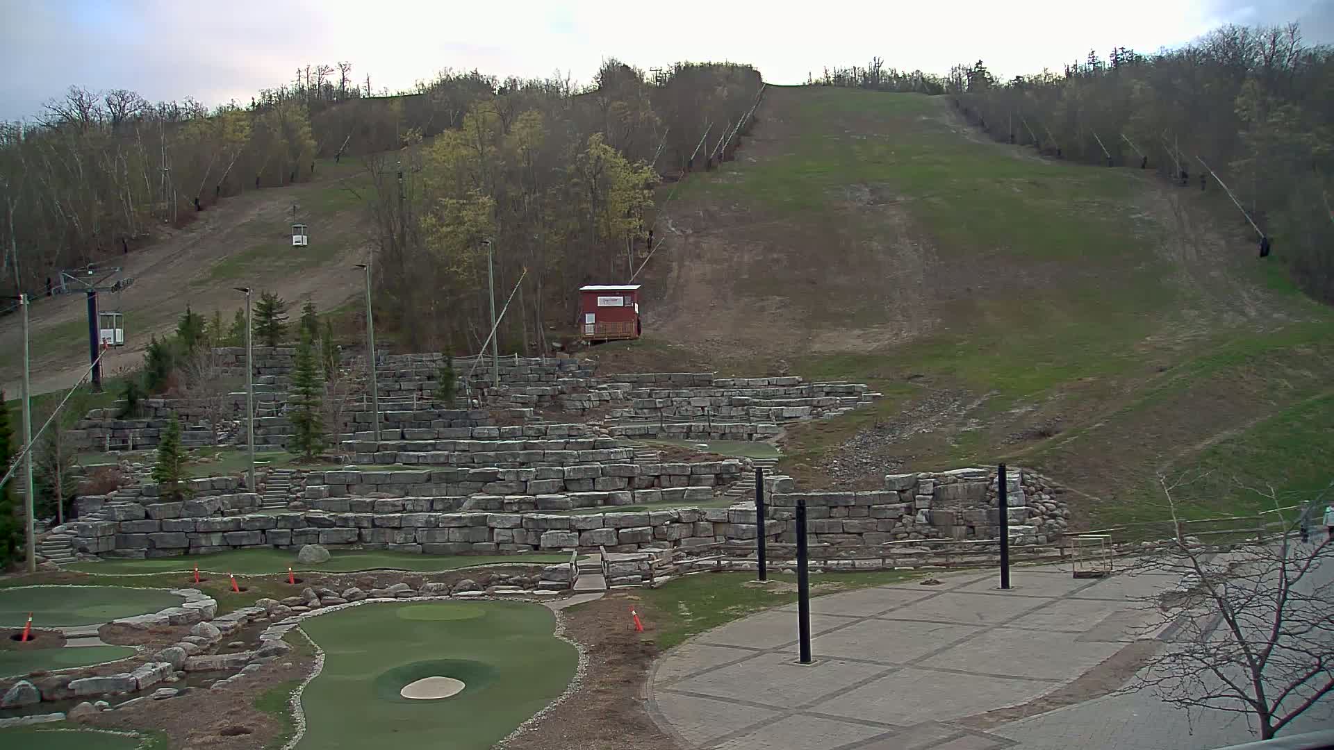 A ski hill with a chairlift and a mini golf course built into a stone retaining wall is visible under an overcast sky.