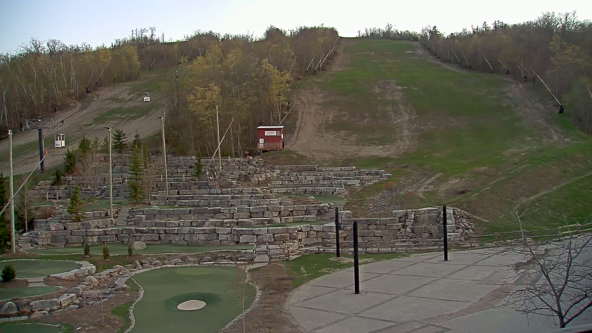 A grassy hillside with a ski lift and a stone mini-golf course is visible under a clear sky.