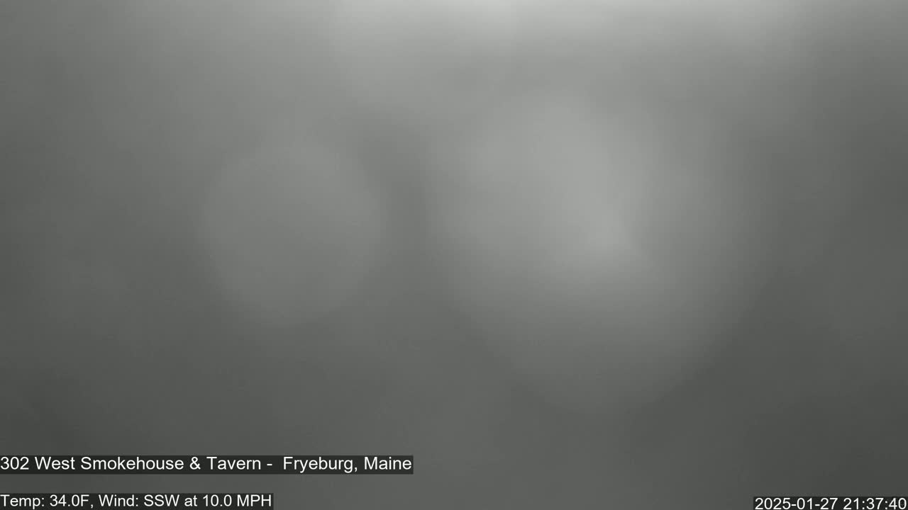 A blurry, gray image shows an overcast sky with a south-southwest wind at 10 mph and a temperature of 34°F.