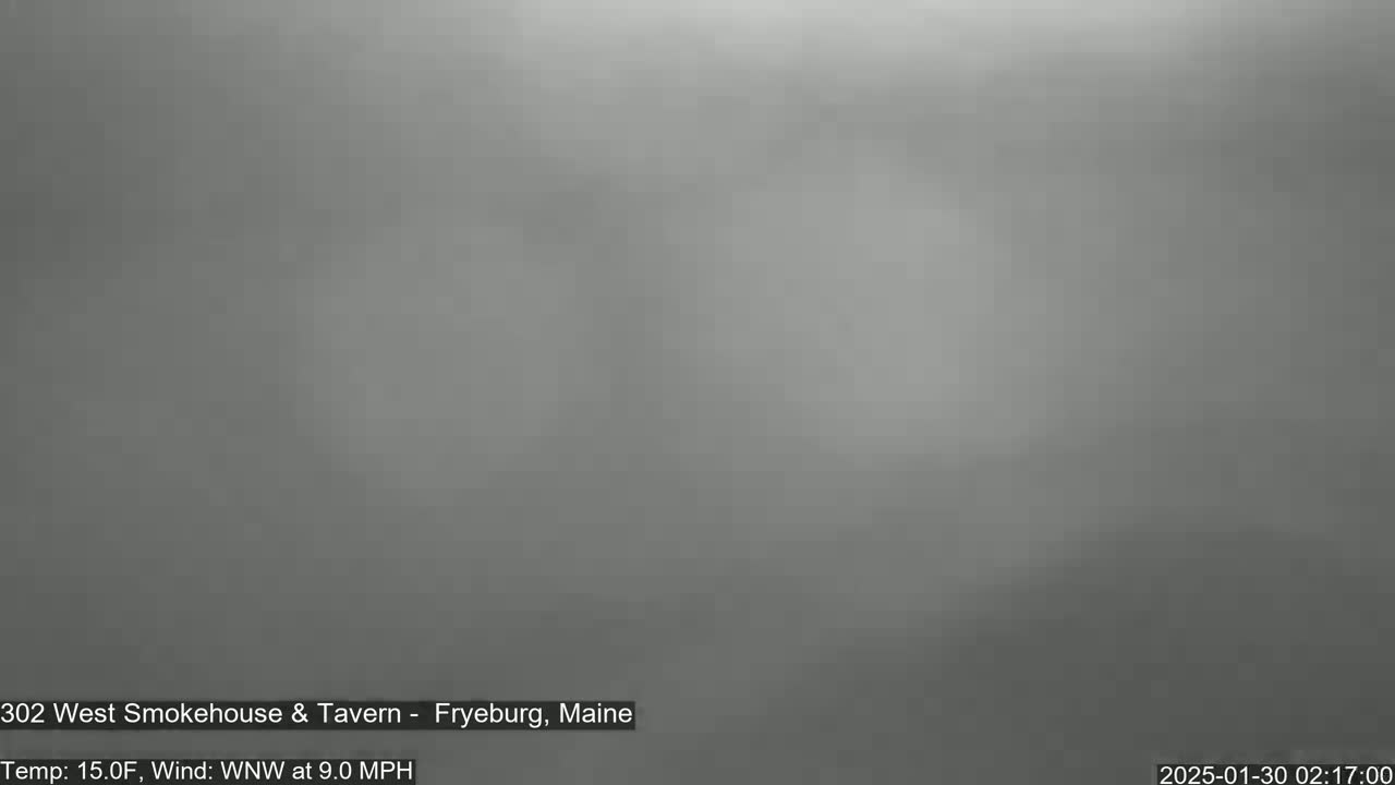 A blurry, gray image shows an overcast sky with a temperature of 15 degrees Fahrenheit and a wind of 9 miles per hour from the west-northwest.