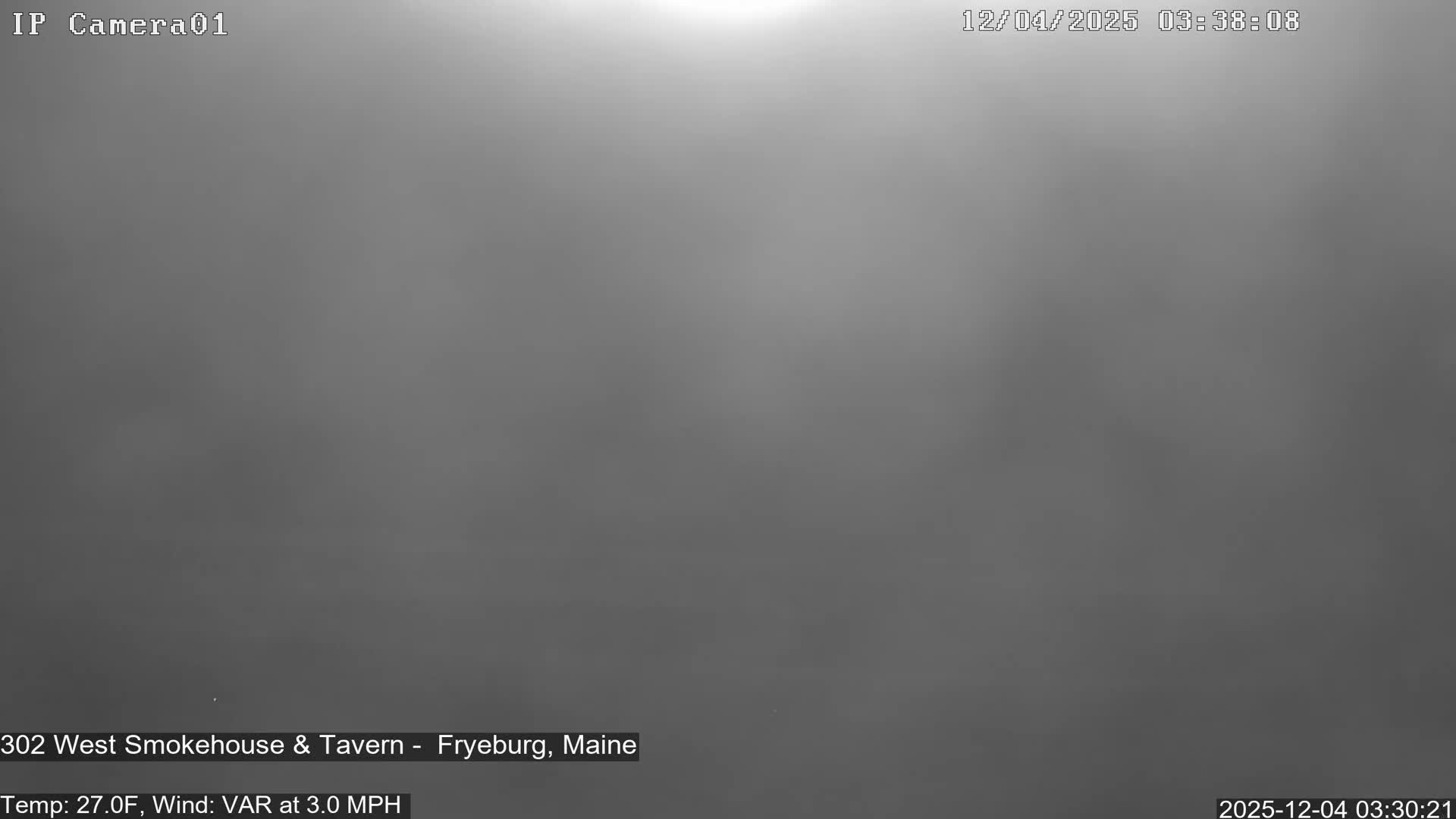 The image displays an outdoor scene completely obscured by dense fog or mist under dark conditions, rendered in a uniform dark gray with a faint lighter glow at the top edge.