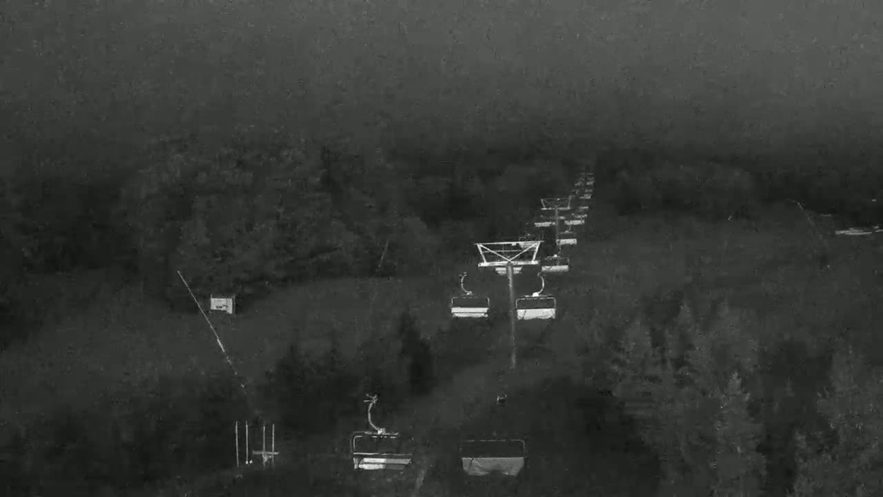 A chairlift ascends a foggy, wooded hillside.