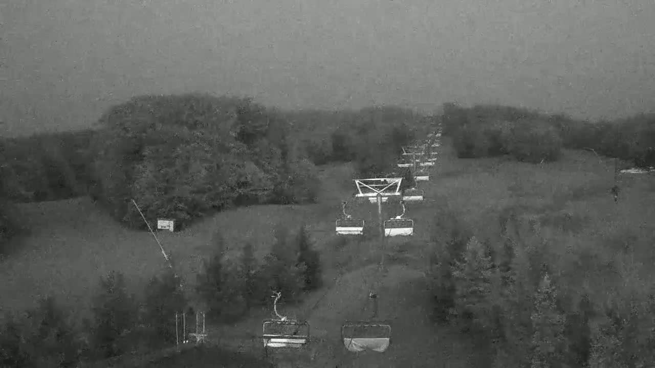 A chairlift extends across a hilly landscape under an overcast sky.