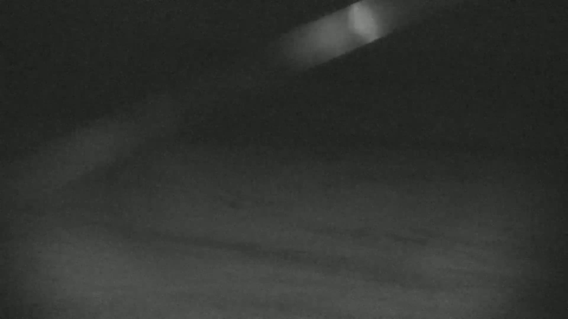 A dark, blurry image shows a dimly lit, possibly outdoor, space with a bright light source in the upper right corner.