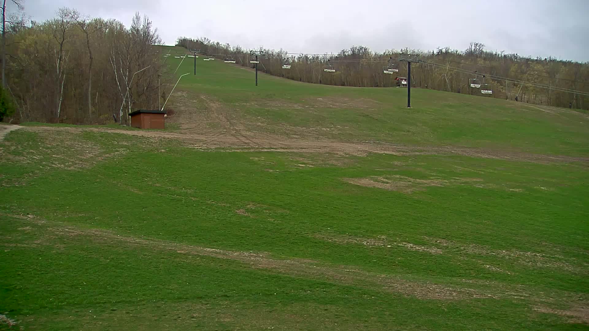 A grassy ski slope with several chairlifts is visible under an overcast sky.