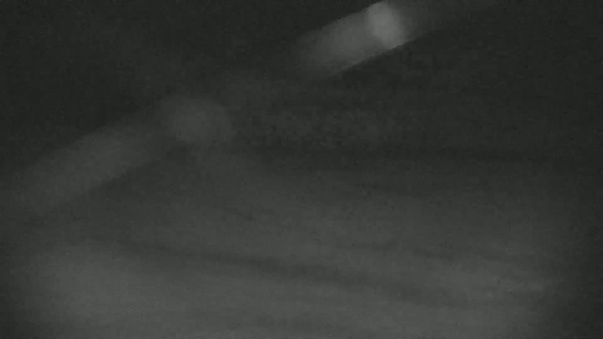 A blurry, dark gray image shows a shadowed surface with a bright, indistinct light source.