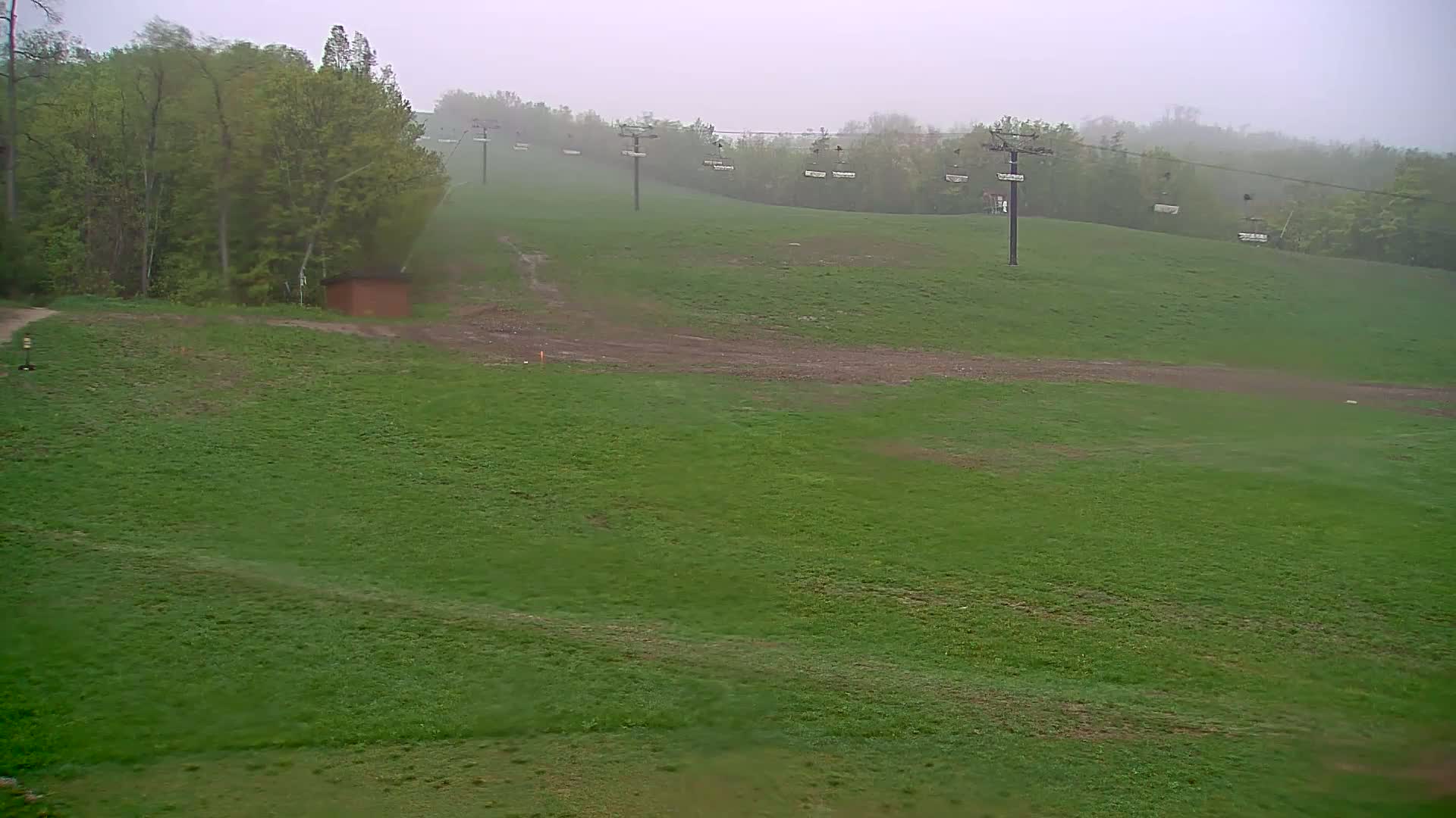 A grassy hillside with a chairlift in the background is visible on an overcast day.
