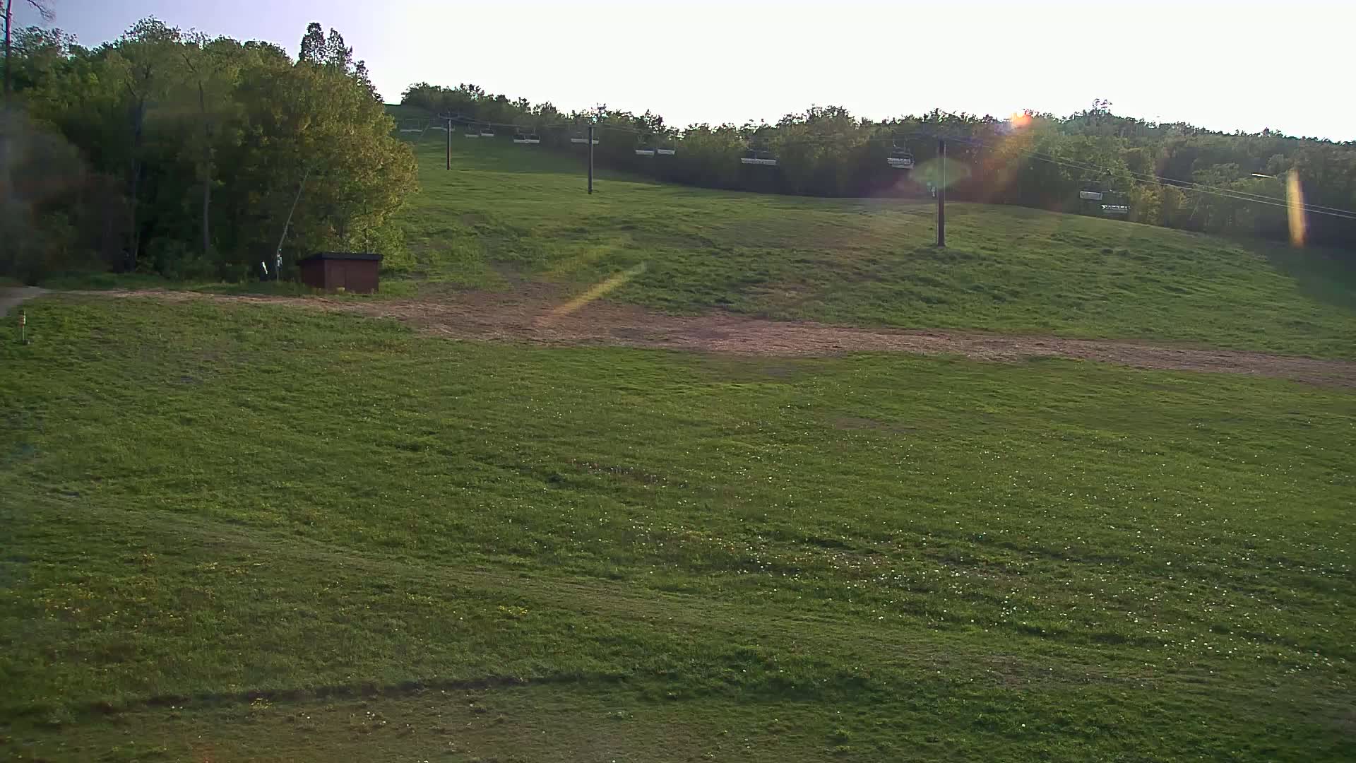 A grassy hillside with a chairlift in the background under bright, sunny conditions.