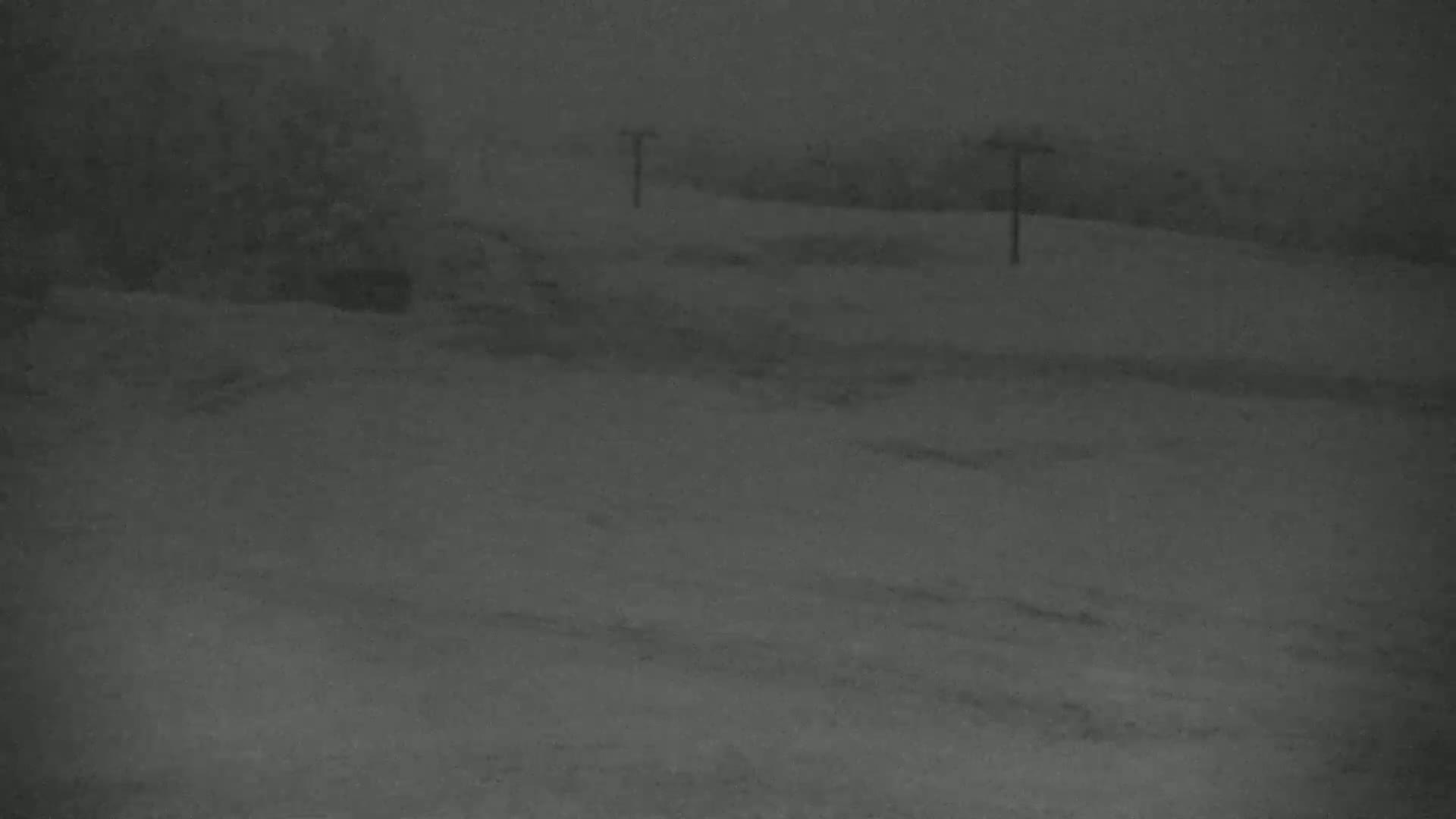 A snow-covered landscape is visible under dark, overcast conditions, with a few tall posts standing in the middle ground.