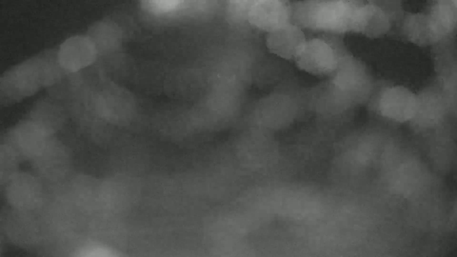 The image shows a blurry, out-of-focus scene of dark gray and lighter gray areas resembling clouds or fog.