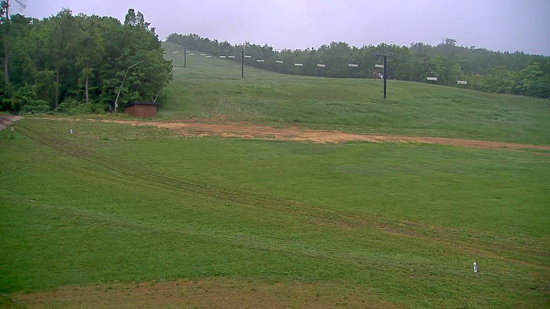 A grassy field with a chairlift in the background under an overcast sky.