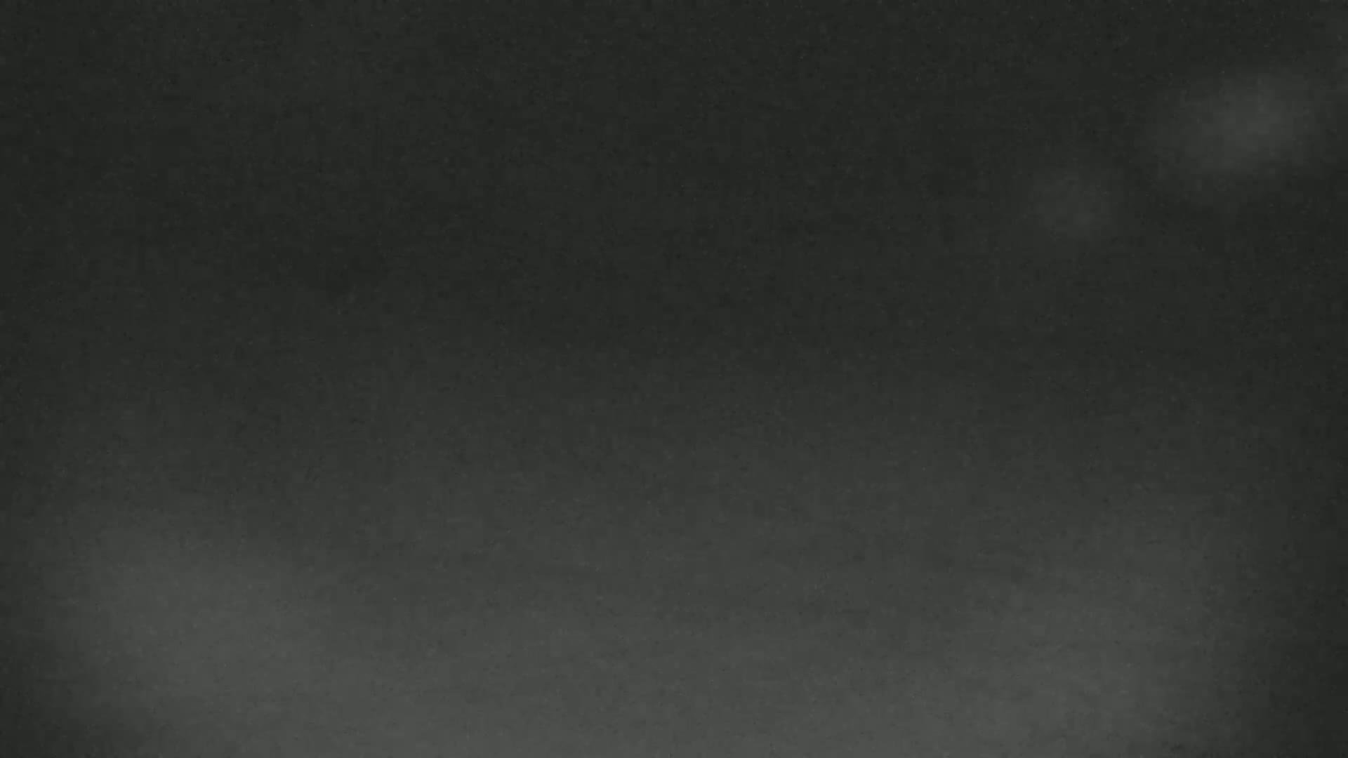 A dark, possibly nighttime, image shows a mostly featureless sky with a few faint, hazy light sources.