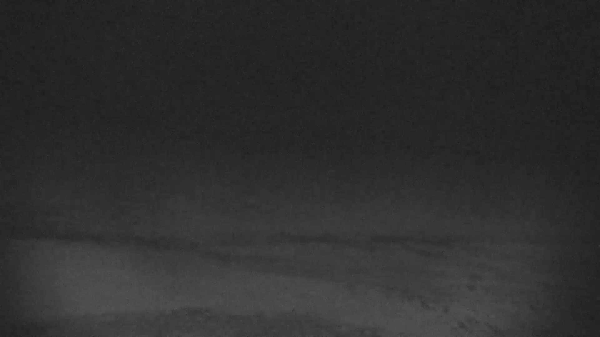 A dark, possibly nighttime, image shows a mostly featureless sky with a few faint, hazy light sources.