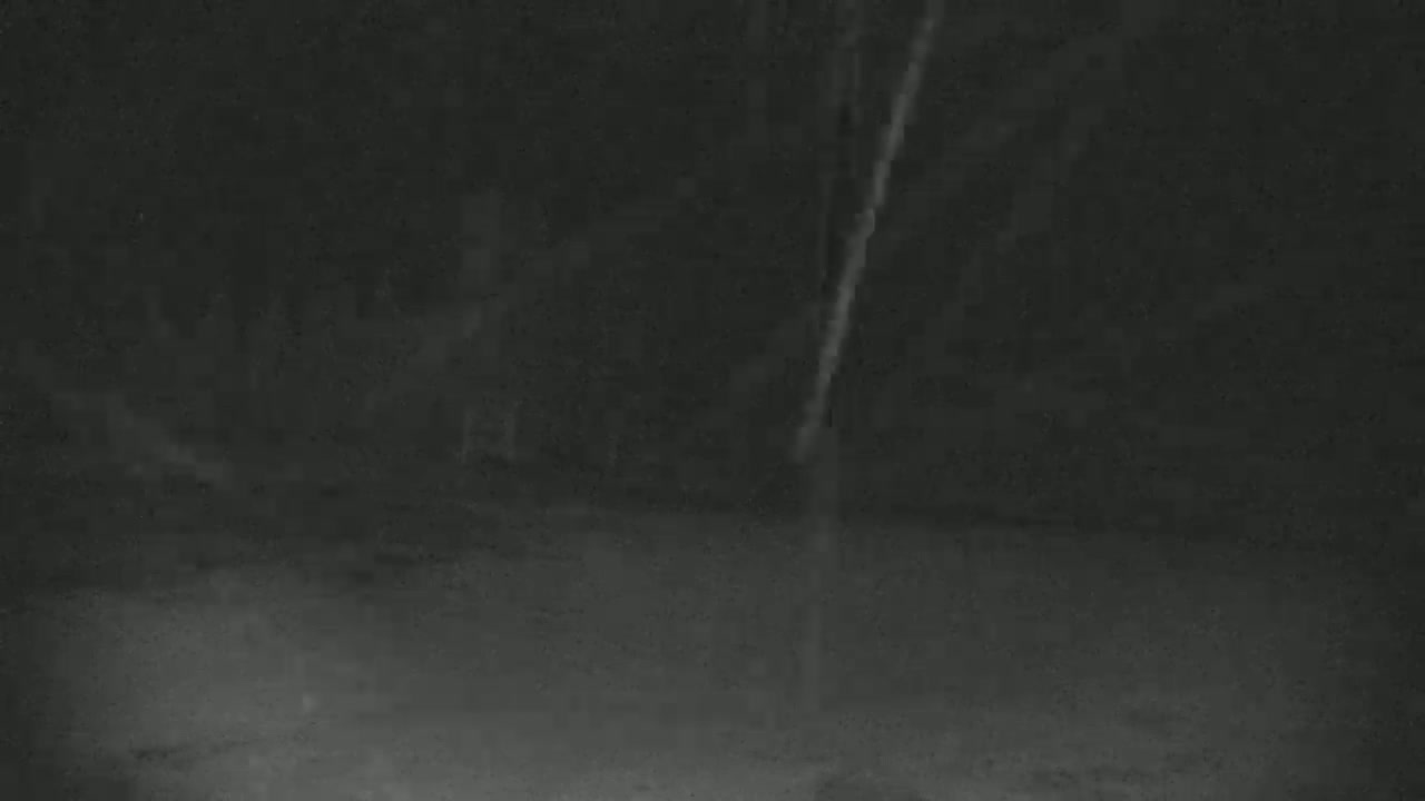 A blurry, dark image shows a nighttime outdoor scene with what appears to be light snow or falling particles.