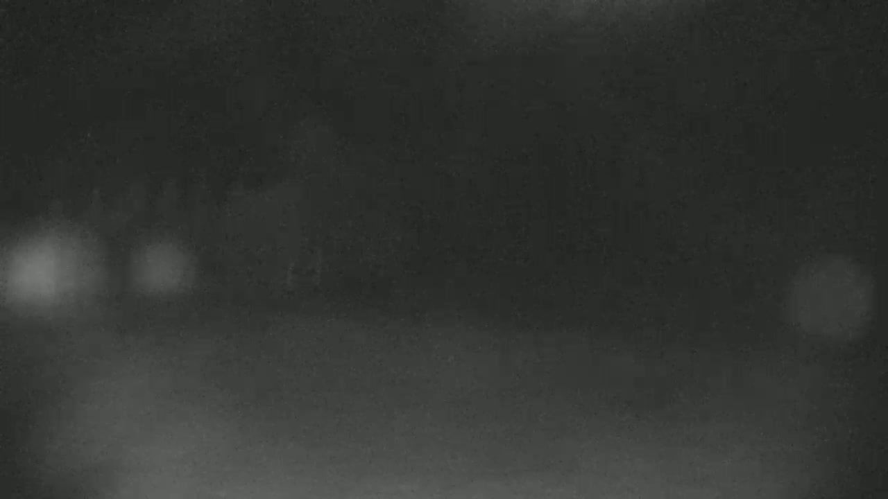 A blurry, dark nighttime image shows indistinct shapes and out-of-focus lights.