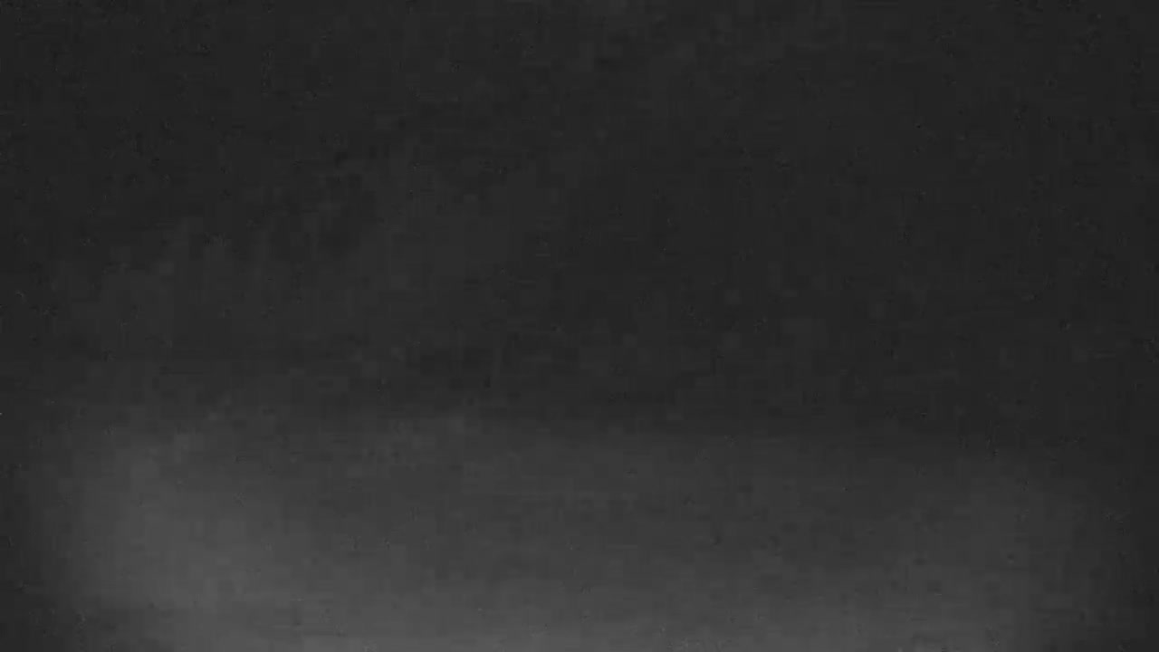 The image is almost entirely dark, appearing as a slightly textured black or very dark gray field, with an extremely faint gradient of light towards the bottom.