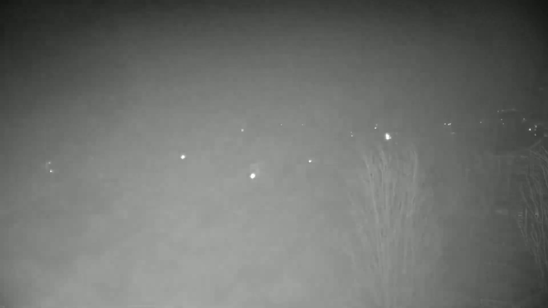 A hazy, nighttime view shows distant lights through a thick fog.