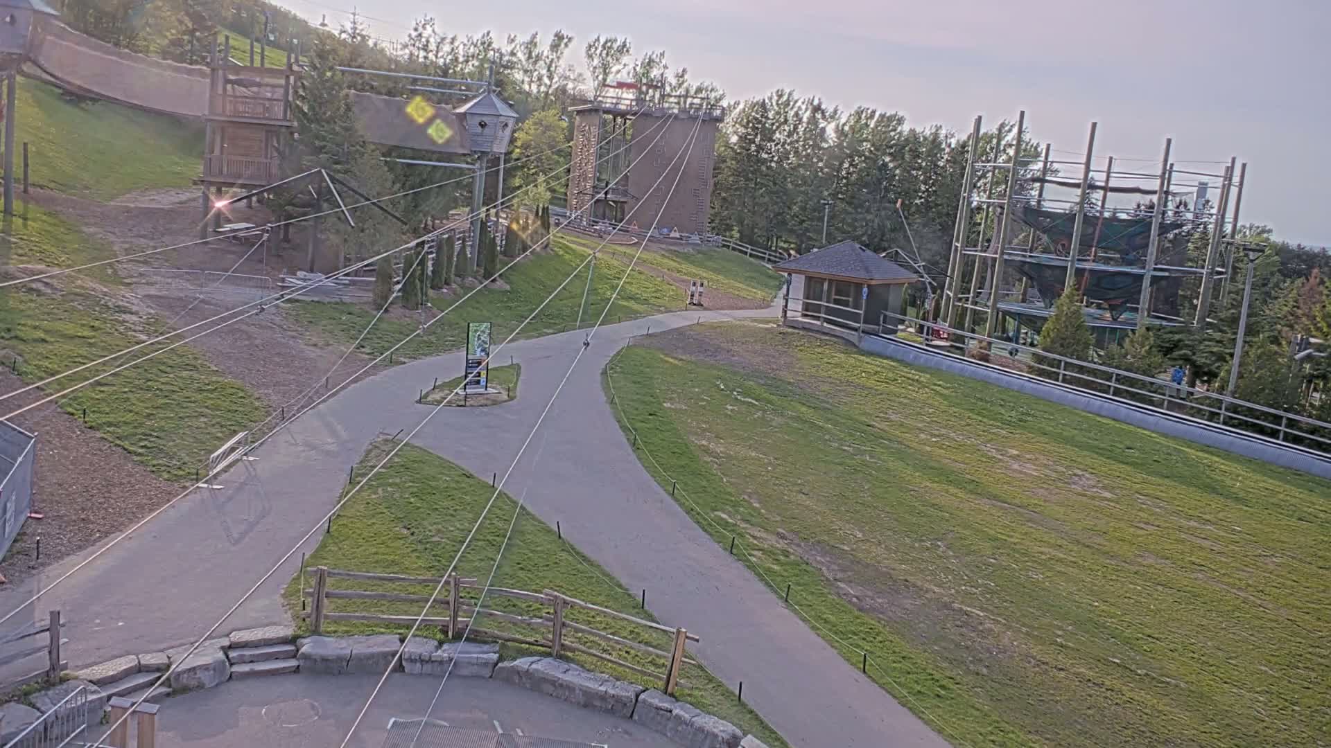 An outdoor ropes course and playground area with paved pathways are visible on a sunny day.
