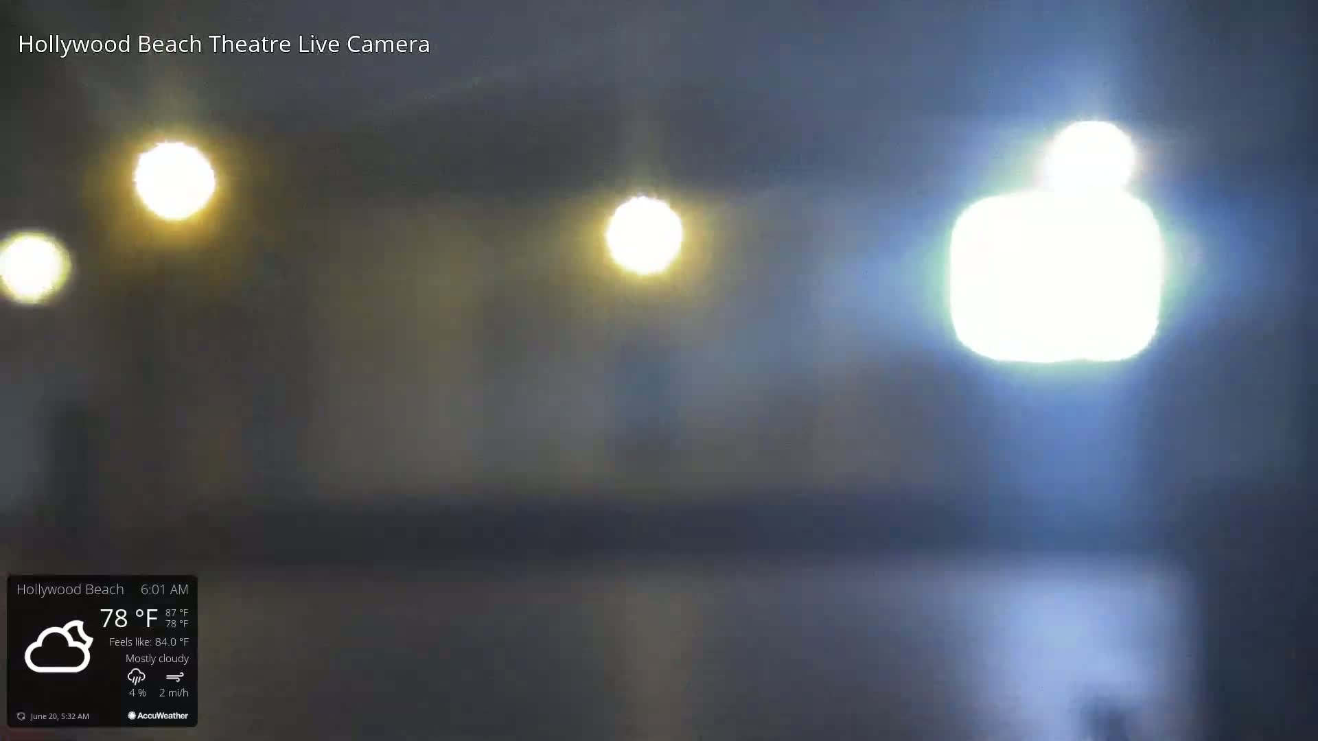 A blurry, mostly cloudy night scene is illuminated by several bright lights.