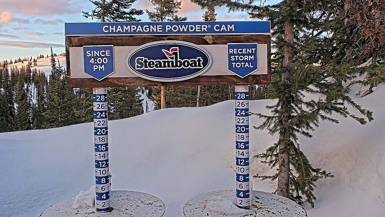A snow depth gauge shows recent snowfall in a snowy mountainous landscape under a twilight sky.