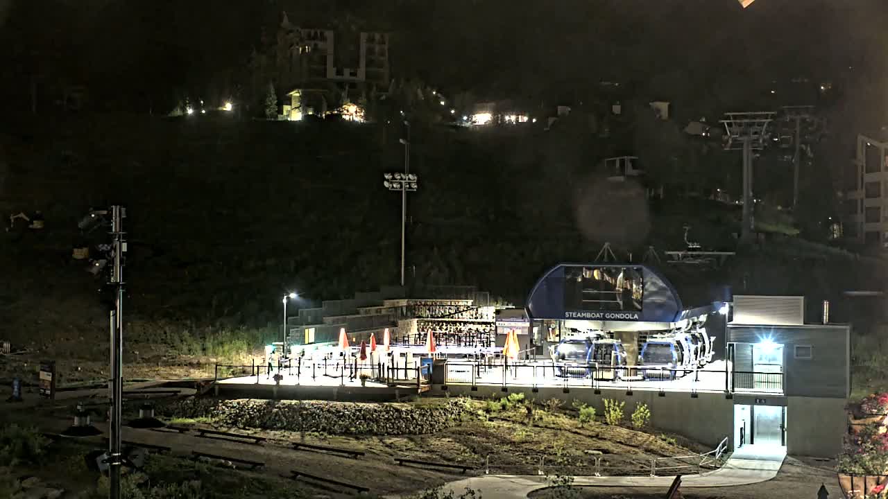 A gondola station and lift illuminated at night on a hillside.