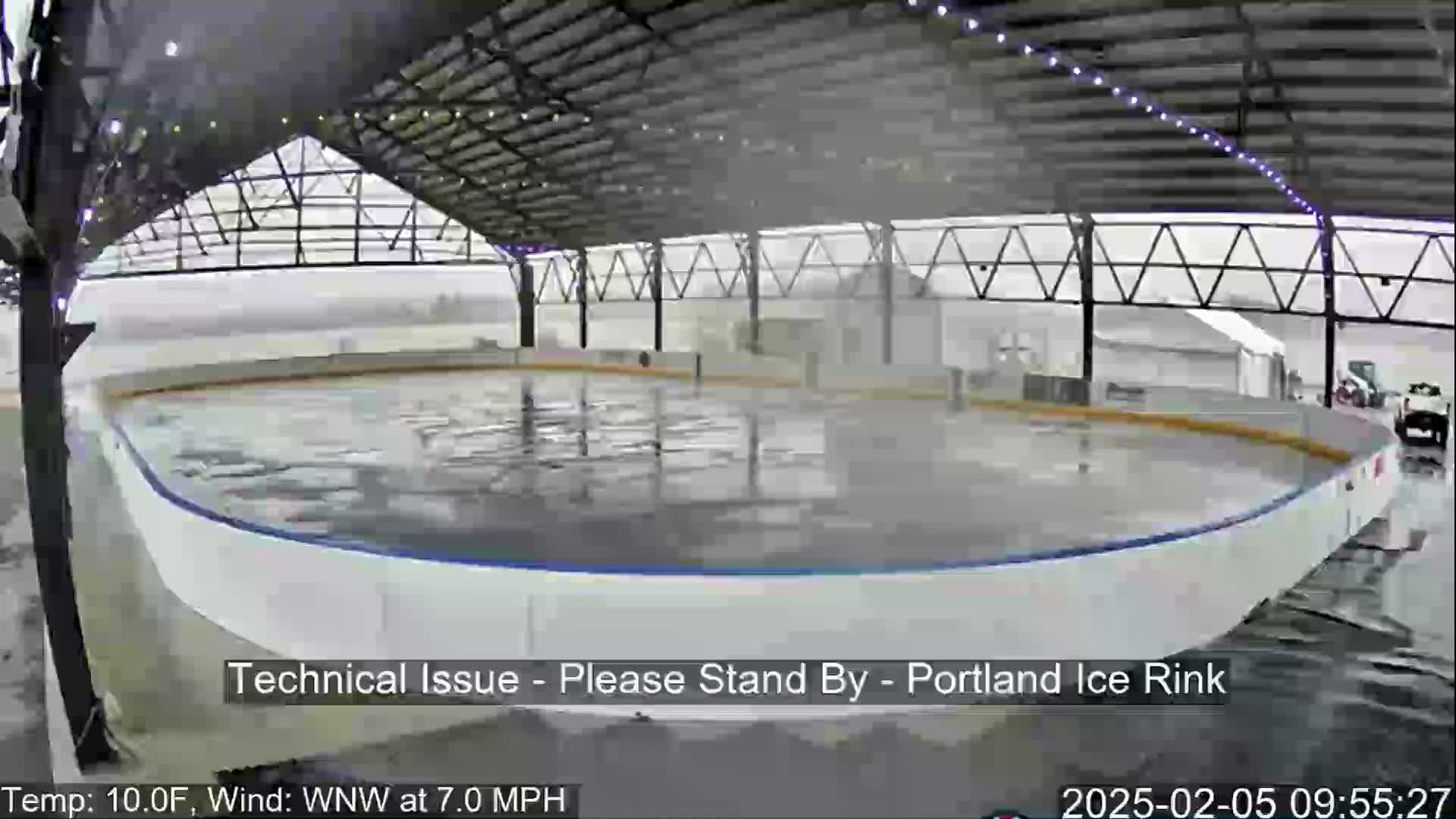An outdoor ice rink under a covered structure is being rained on.