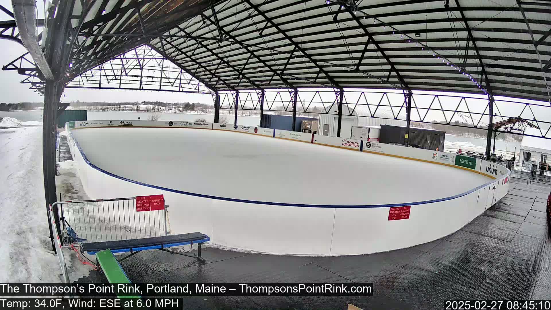 A covered outdoor ice rink, partially surrounded by snow, with a 6.0 mph ESE wind and a temperature of 34.0°F.