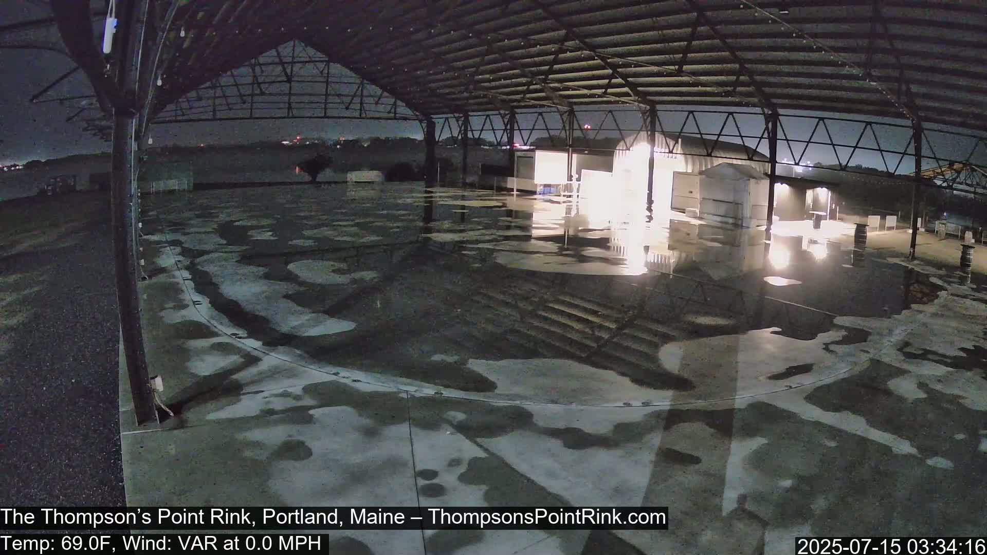 A wet, empty rink under a metal roof at night.