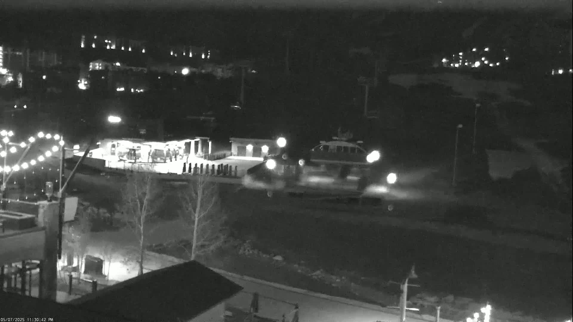A hovercraft passes by a building at night, leaving a trail of vapor in the dark, snowy surroundings.