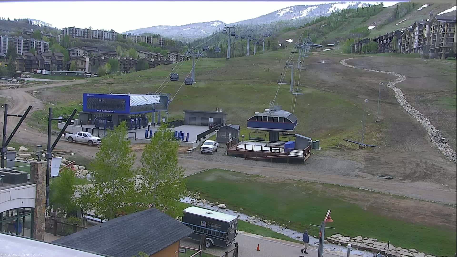 A ski lift base area with several chairlifts ascending a grassy mountainside under an overcast sky.