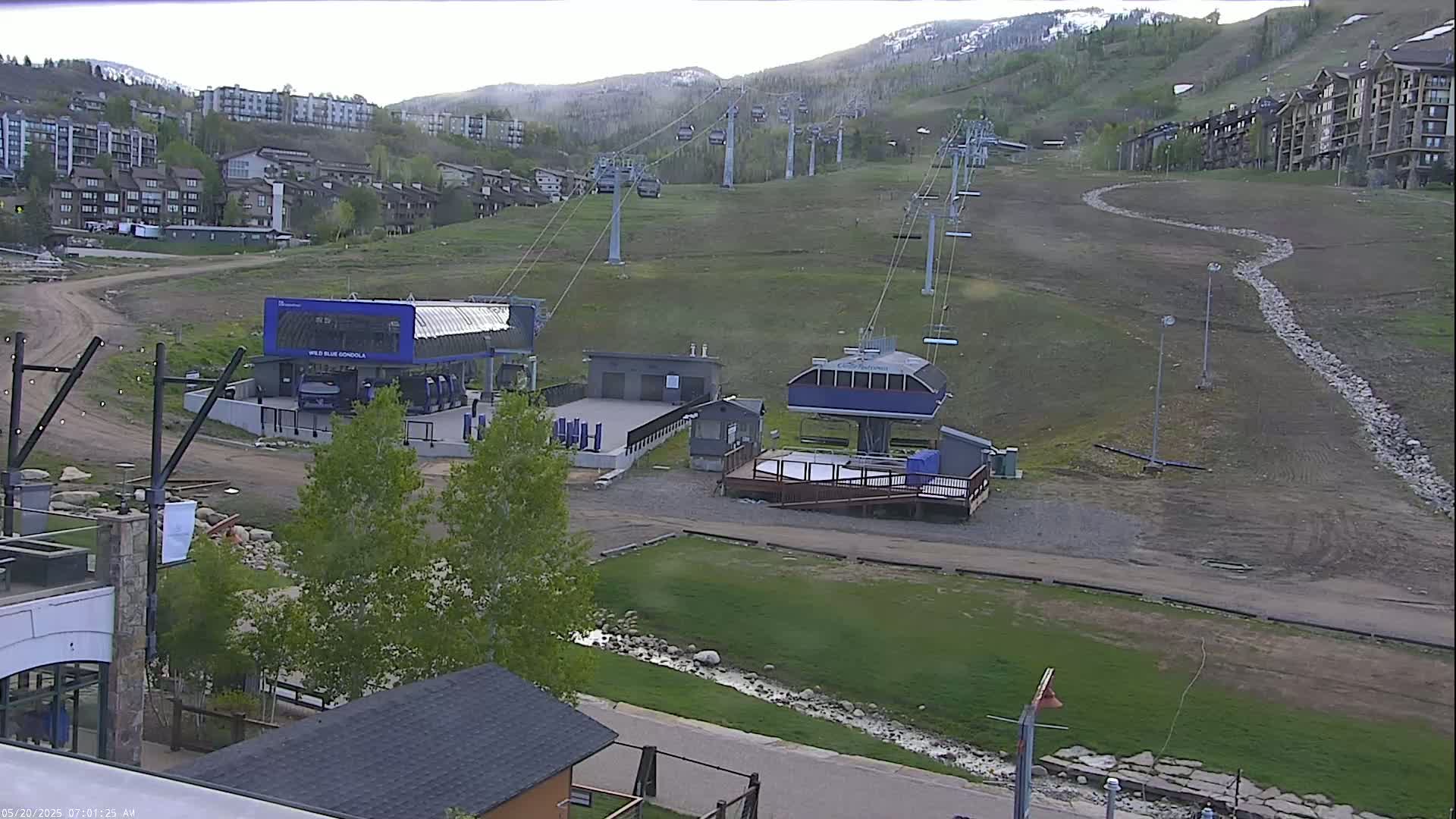 A ski lift base area with several chairlifts ascending a grassy mountainside under an overcast sky.