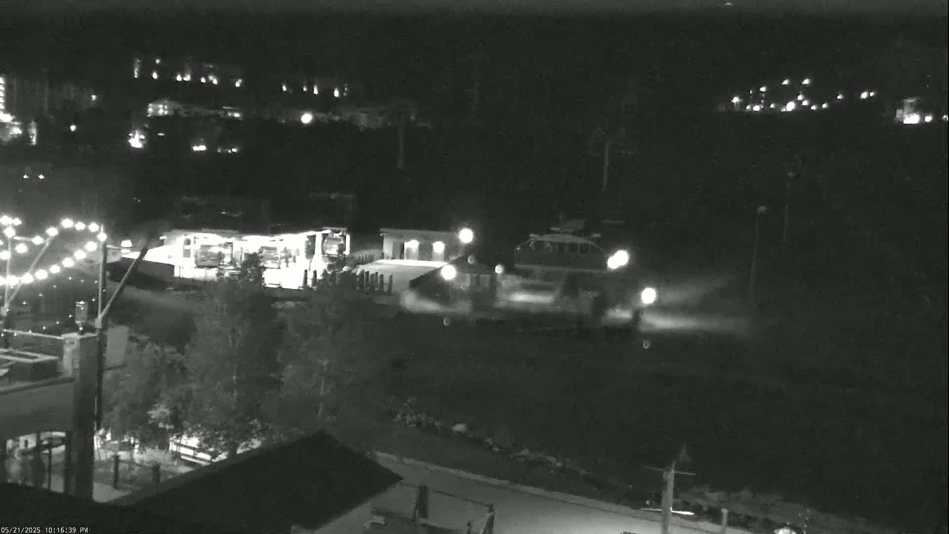 At night, several vehicles are parked near a building, with some lights illuminated in the surrounding area.
