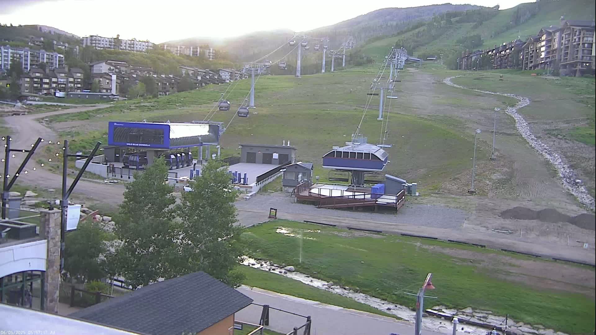 A mountainside ski resort with chairlifts and gondola stations is visible on a partly sunny day.
