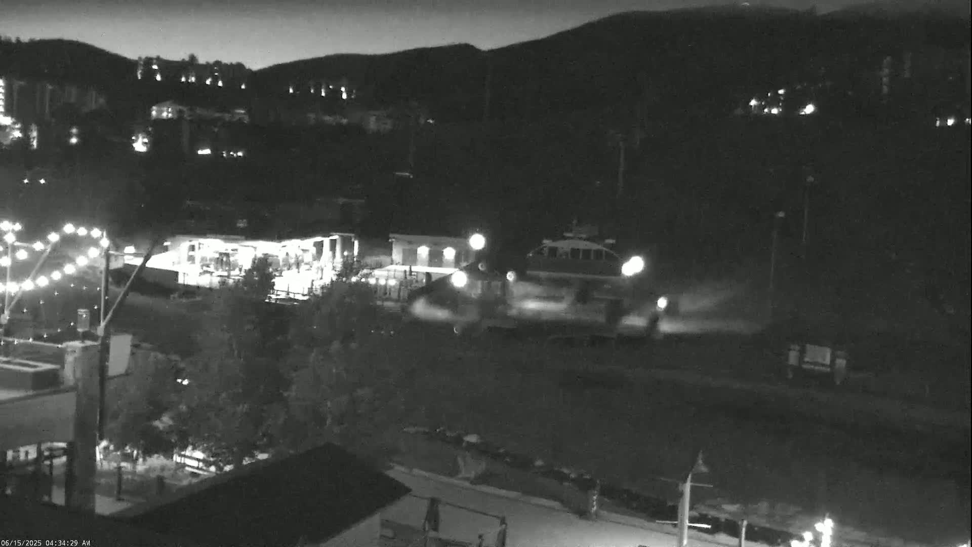 A nighttime, low-light view shows a vehicle moving through a town nestled in a mountain valley.