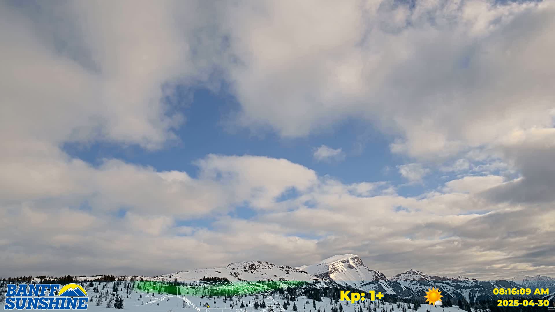 A partly cloudy sky with scattered clouds over snow-covered mountains.