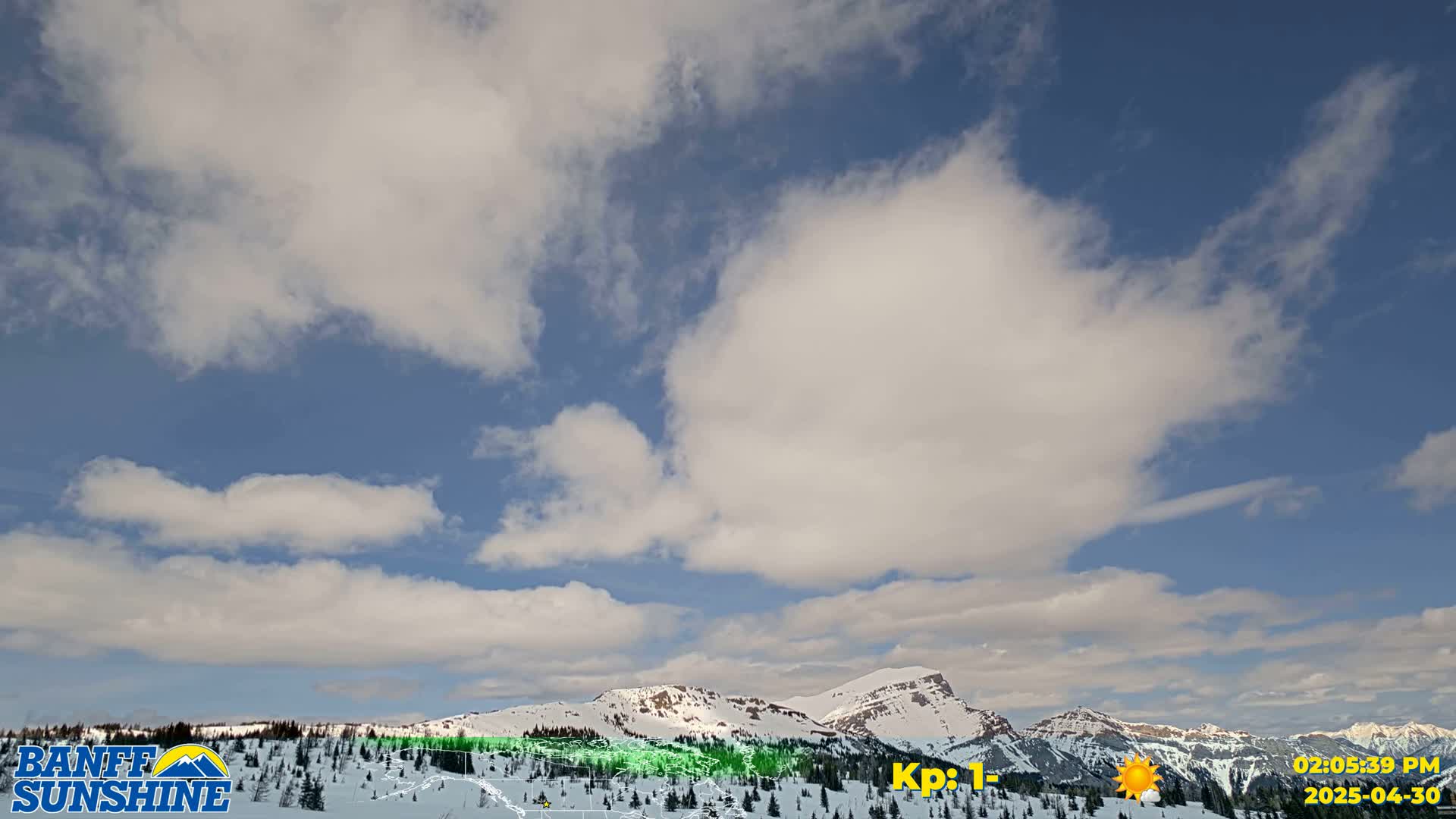 A partly cloudy sky over snow-covered mountains.