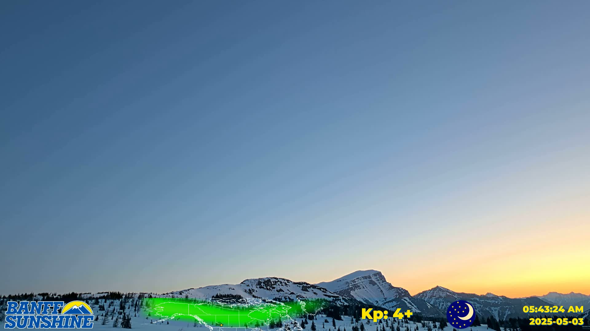 A clear twilight sky over snow-covered mountains, with a hint of orange on the horizon.