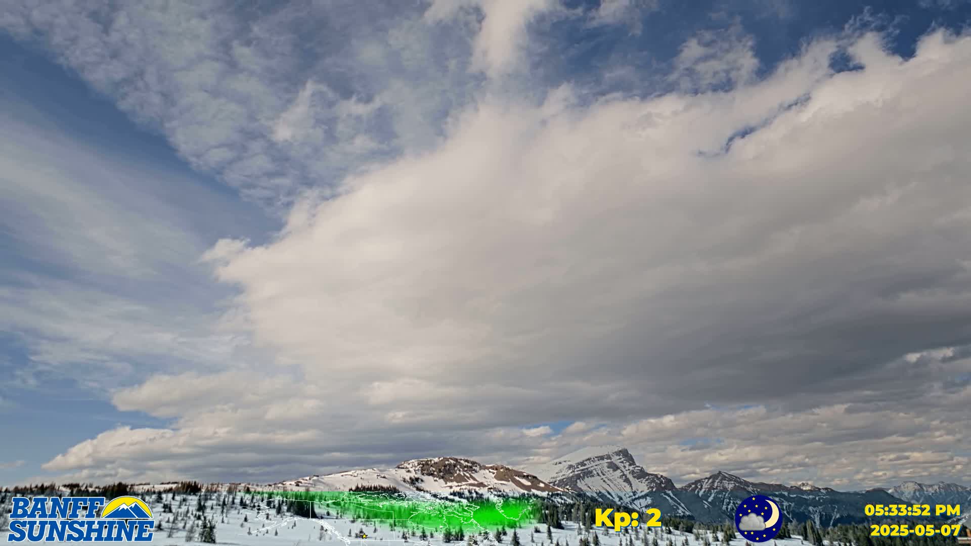 A mostly cloudy sky hangs over snow-covered mountains.
