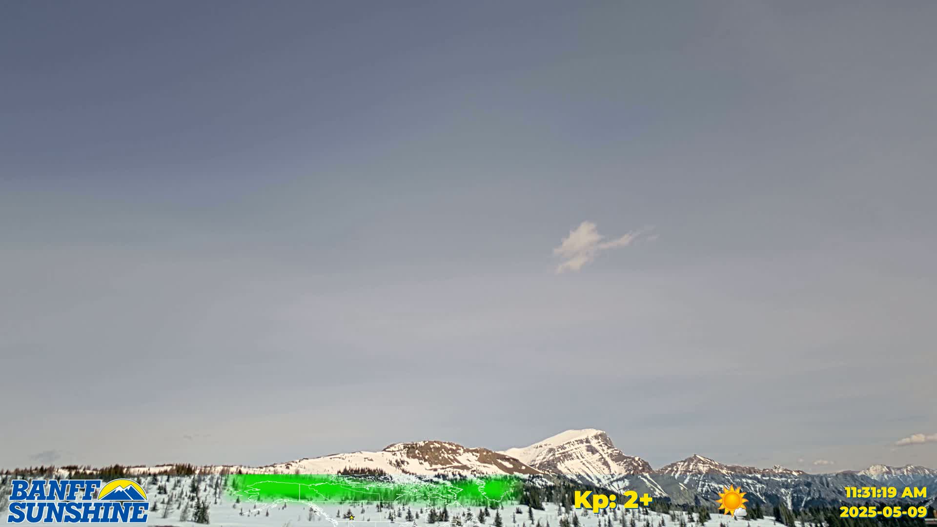 A mostly clear sky over snow-covered mountains.